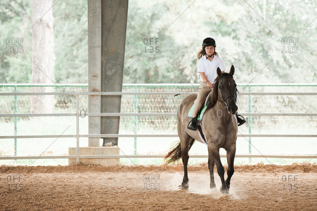 Girl practicing with her horse in an equestrian arena