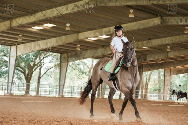 Girl riding her horse for practice in an equestrian arena