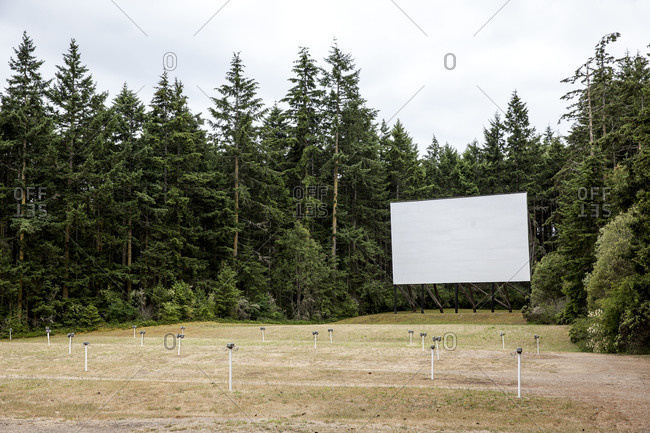 Empty field with a drive-in movie screen and speakers