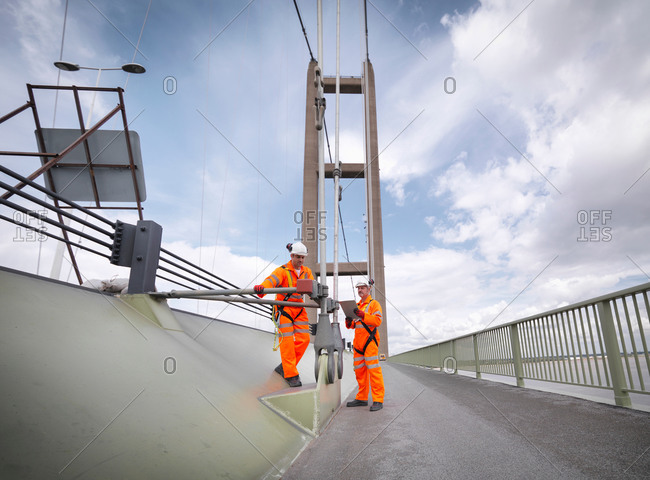 Bridge workers inspecting suspension bridge cables