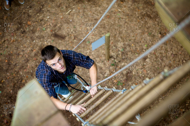 Man climbing a ladder of a ropes course