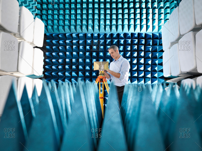 Male scientist preparing to measure electromagnetic waves in anechoic chamber