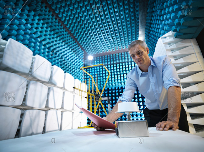 Scientist preparing to measure electromagnetic waves in anechoic chamber, low angle view