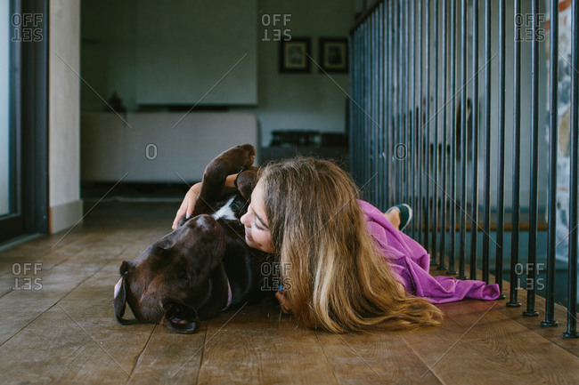 Girl lying on floor hugging dog