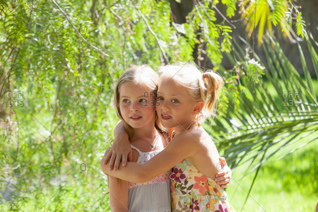 Two girls with arms around each other in garden