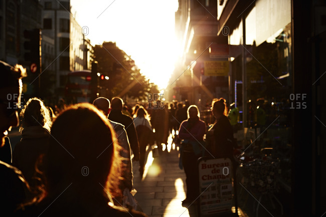 Silhouette of a crowd walking down a city street at sunset