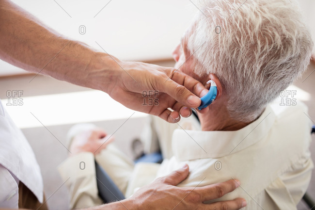 Nurse giving hearing device to a senior man in a retirement home