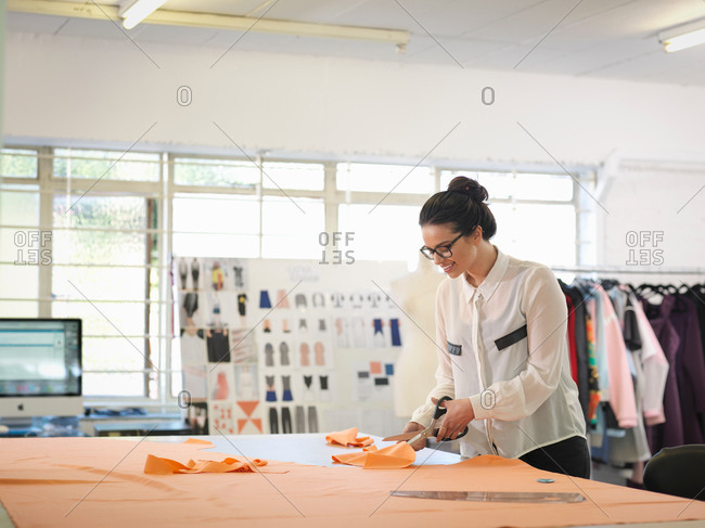 Fashion designer cutting cloth in fashion design studio