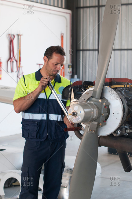 Mid adult male aircraft mechanic working on airplane in hangar
