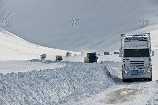 Trucks driving on snow covered highway 1, Oxnadalsheidi, North Iceland