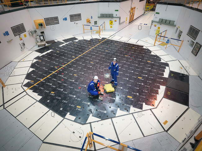 Engineers using sensors on pile cap in nuclear power station, high angle view