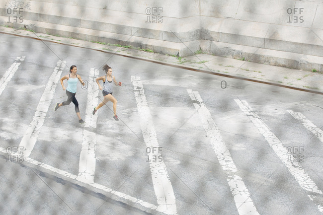 Two women sprinting down a street as seen from an above angle