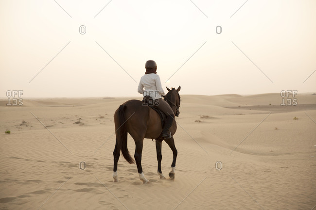 Woman riding horse in desert