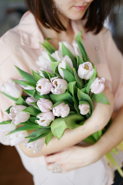 Woman with bunch of pale pink tulips in her arms