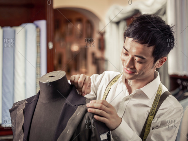 Trainee tailor pinning garment in traditional tailors shop