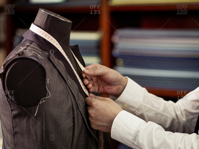 Tailor measuring garment in traditional tailors shop