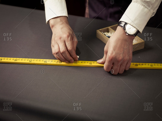 Tailor chalking measurements on table in traditional tailors shop