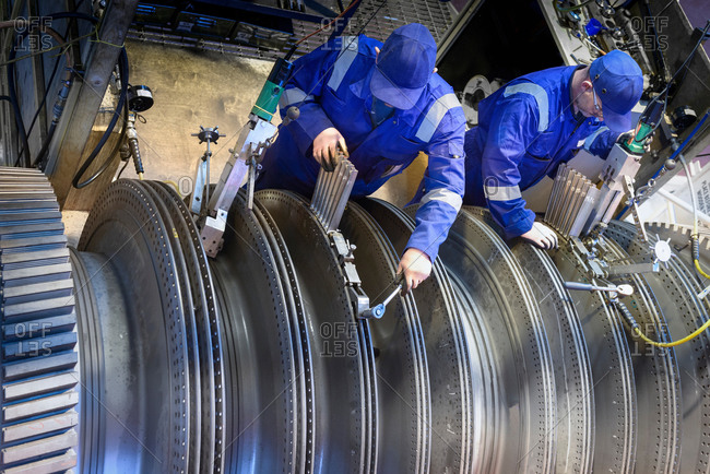 Engineers fitting blades to steam turbine in turbine repair bay