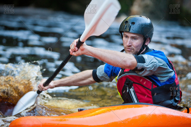 Close up of mid adult man kayaking on river rapids