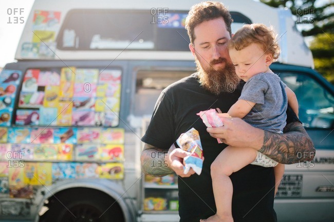 Dad carries child with ice cream from ice cream truck
