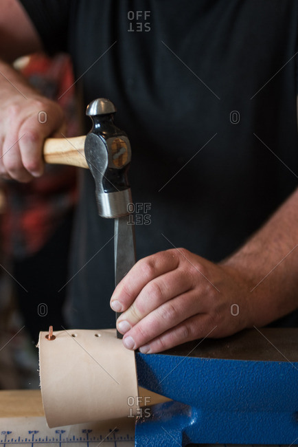 Person working with leather, hammer and chisel