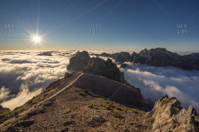 Sun shining above the clouds and peaks of the Pico do Arriero in Madeira, Portugal