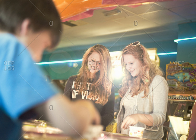 Teenage sisters playing games in amusement arcade