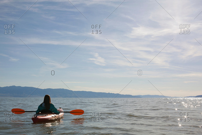 Rear view of young woman kayaker sitting in kayak on water, Great Salt Lake, Utah, USA