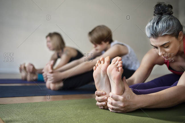 Female touching feet while doing yoga in health club