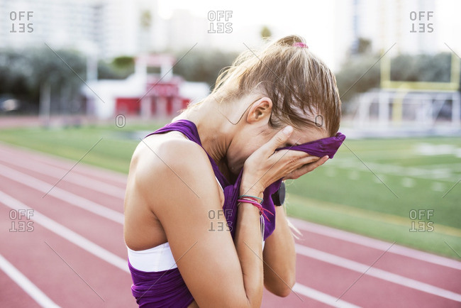 Side view of female athlete wiping sweat on face with tank top