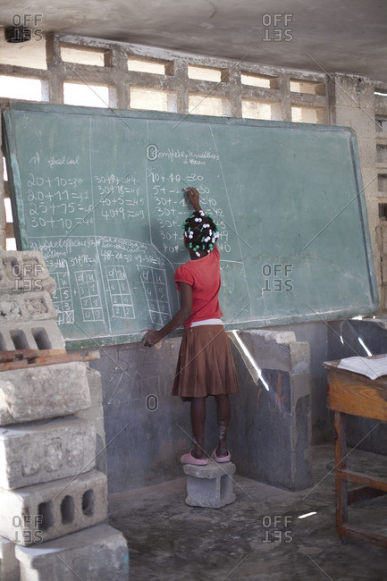 Haitian girl doing math on a classroom chalkboard