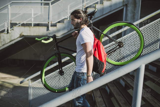 Young man carrying fixie bike on stairs