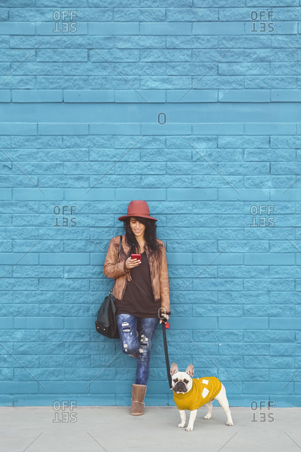 Woman with her French bulldog in front of blue wall