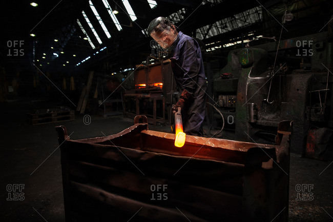 Forge worker preparing to release finished upset forging into steel container