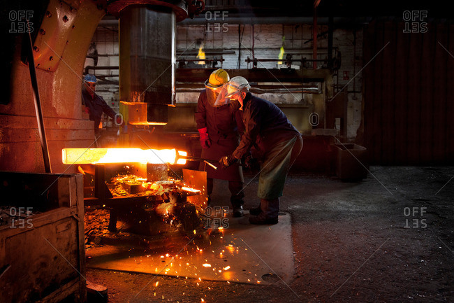 Forge workers pre form red hot billet into flight bar (mining component) on hammer