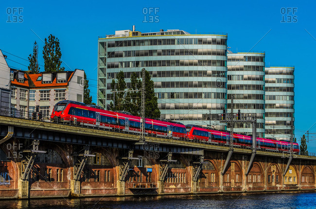 Commuter train along Spree River with office buildings, Berlin, Germany
