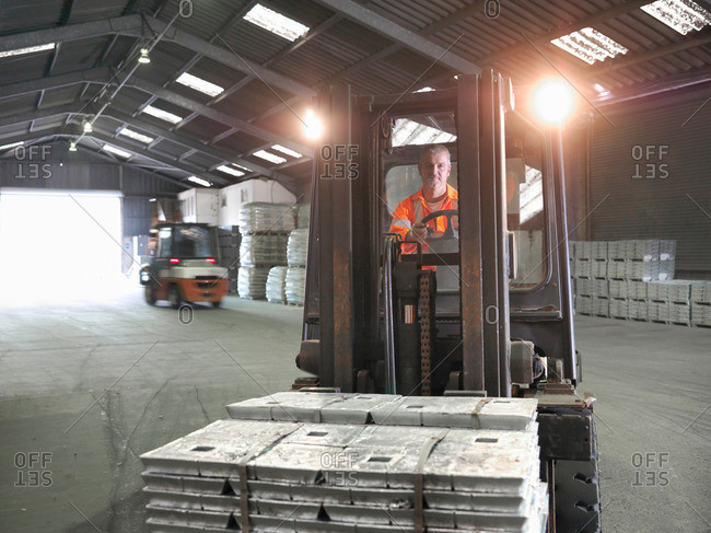 Fork lift driver transporting metal alloy in port store