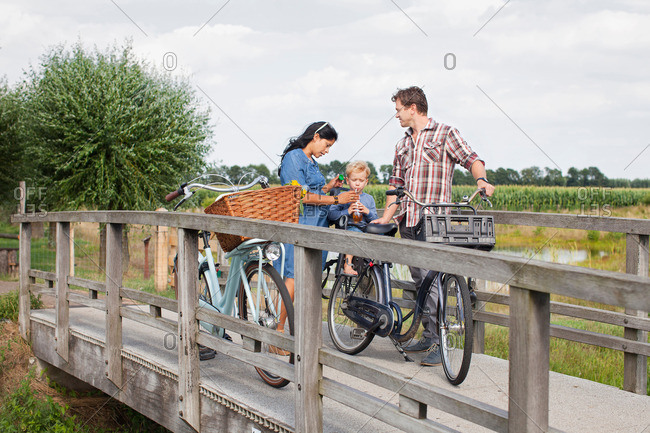 Family on bicycles on wood bridge, stopped for drink