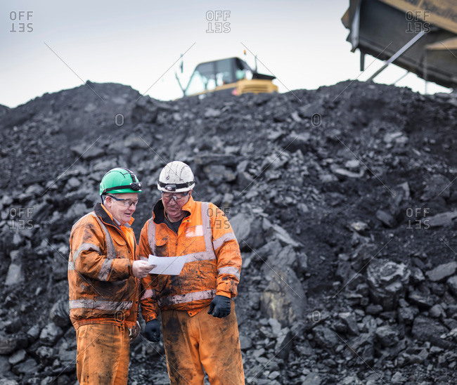 Workers in discussion in front of coal stocks in surface coal mine