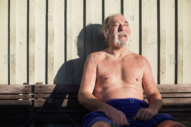 Happy senior man enjoying the warm sunlight after a swim