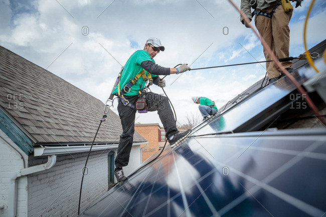 Construction crew installing solar panels on a roof of a house