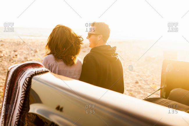 Couple sitting in truck bed on beach, Malibu, California, USA