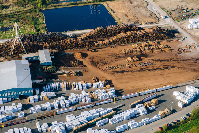 Aerial view of stacked tree trunks and warehouses in timber yard