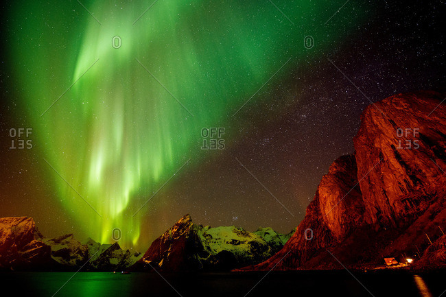 View of aurora borealis over sea and snow capped mountains, Reine, Norway