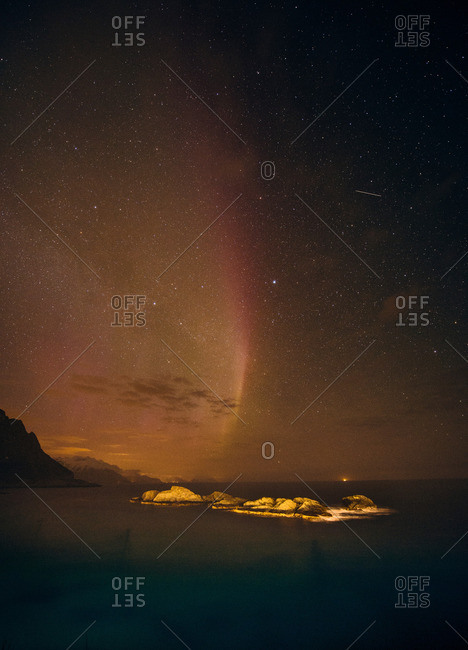 Aurora borealis disappearing over sea horizon, Reine, Norway