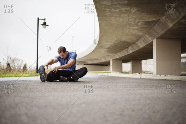Determined man exercising while sitting on street