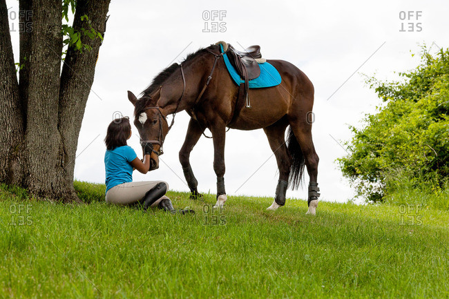 Horse rider sitting beside tree, horse beside