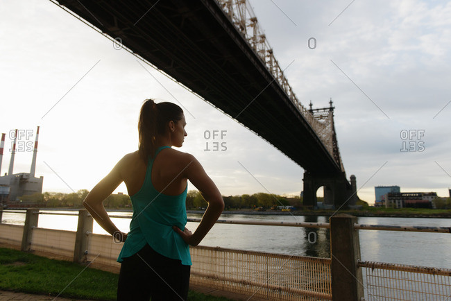 Young female runner with hands on hips on waterfront, Roosevelt Island, New York City, USA