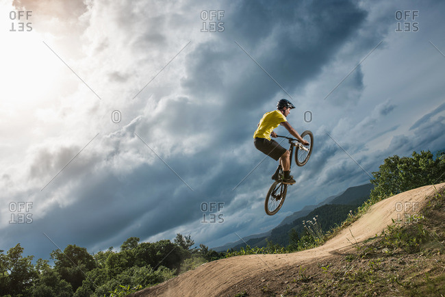 Young male mountain biker jumping mid air on rural pump track