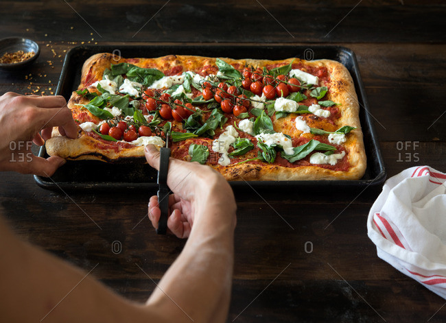 Person cutting Roman-style pizza